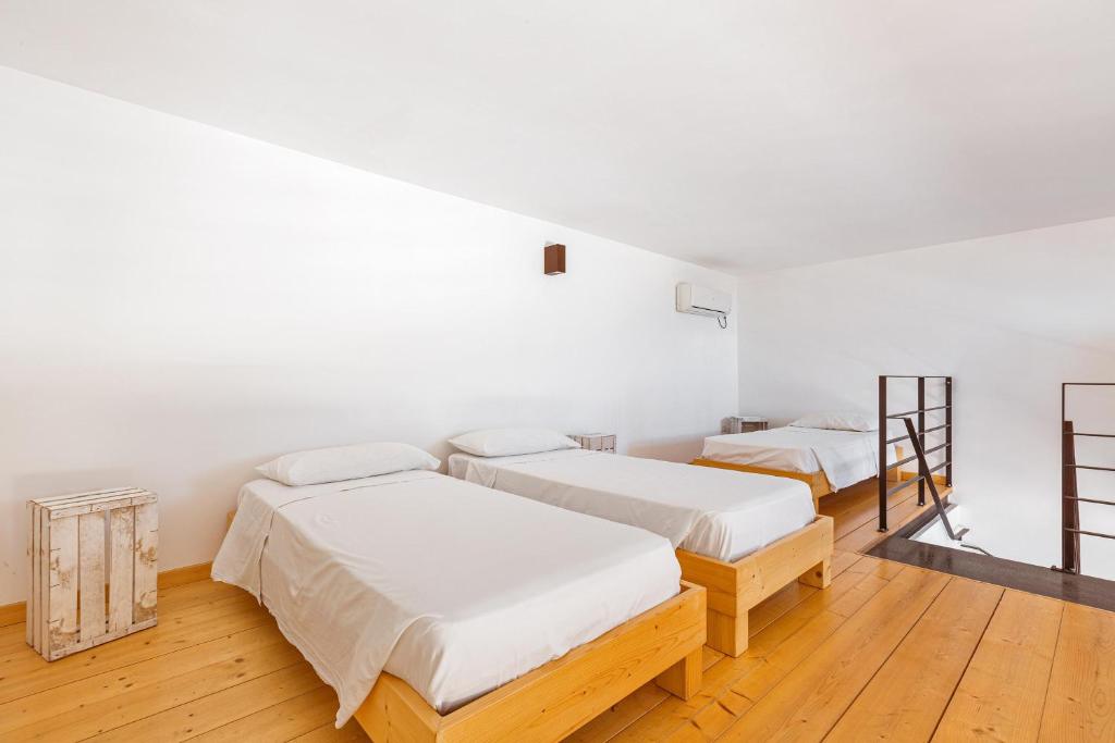 deux lits dans une chambre aux murs blancs et au parquet dans l'établissement Tenuta Terra del Sole by Perle di Puglia, à Ugento