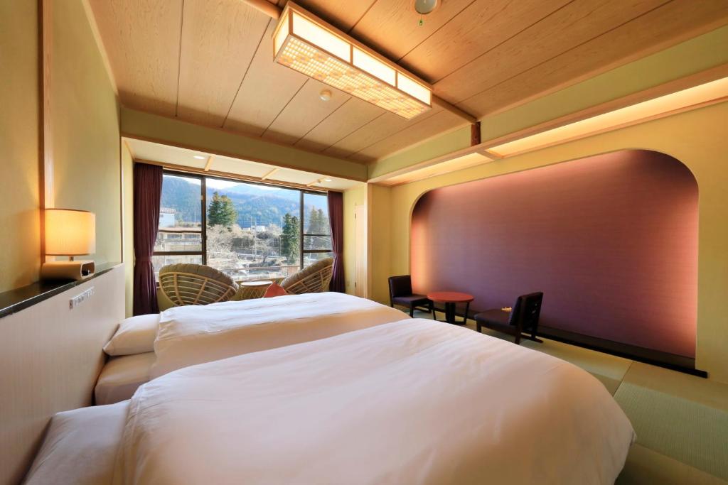 une chambre d'hôtel avec deux lits et une grande fenêtre dans l'établissement Wafu-no-Yado MASUYA, à Yamanouchi 37 autres photos