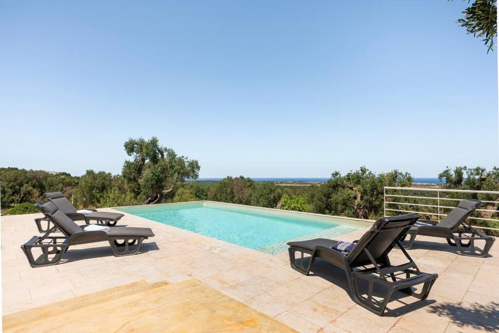 une piscine avec deux chaises et une piscine dans l'établissement The Peak House, à Carovigno