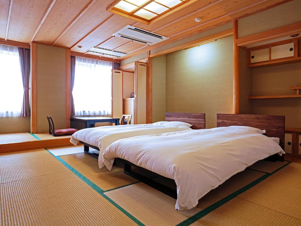 une chambre avec deux lits dans une pièce dans l'établissement Oyado Kinkiyu Annex SUIKAZURA, à Teshikaga