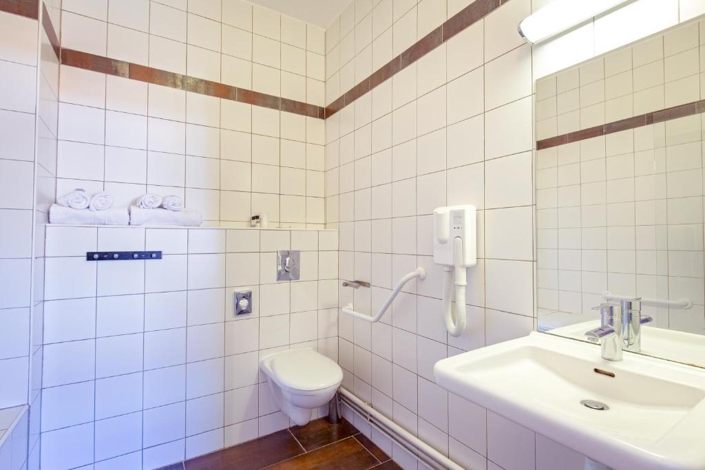 La salle de bains est pourvue de carrelage blanc, de toilettes et d'un lavabo. dans l'établissement SOWELL HOTELS Le Pas du Loup, à Isola 2000 37 autres photos