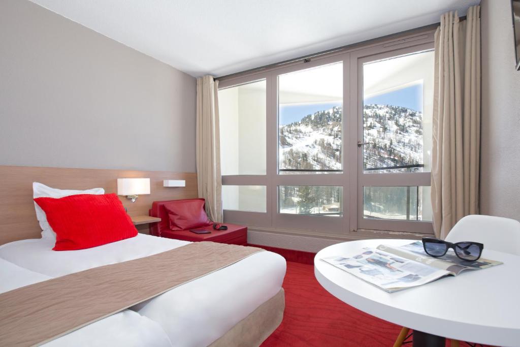 une chambre d'hôtel avec un lit et une grande fenêtre dans l'établissement SOWELL HOTELS Le Pas du Loup, à Isola 2000
