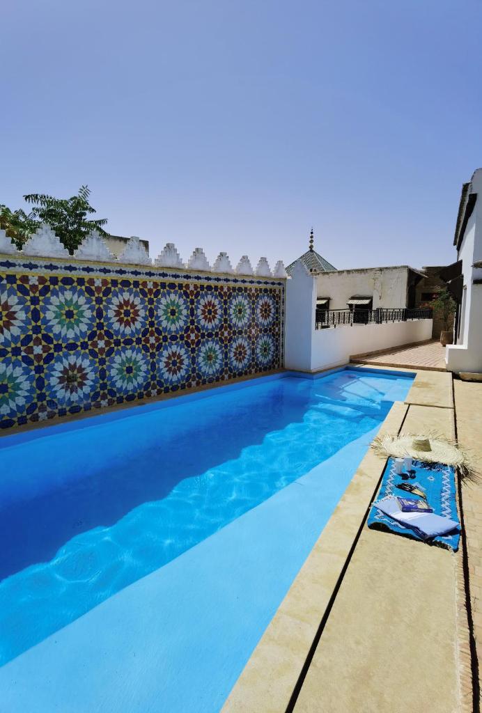 une piscine d'eau bleue et un mur dans l'établissement Palais didi, à Meknès