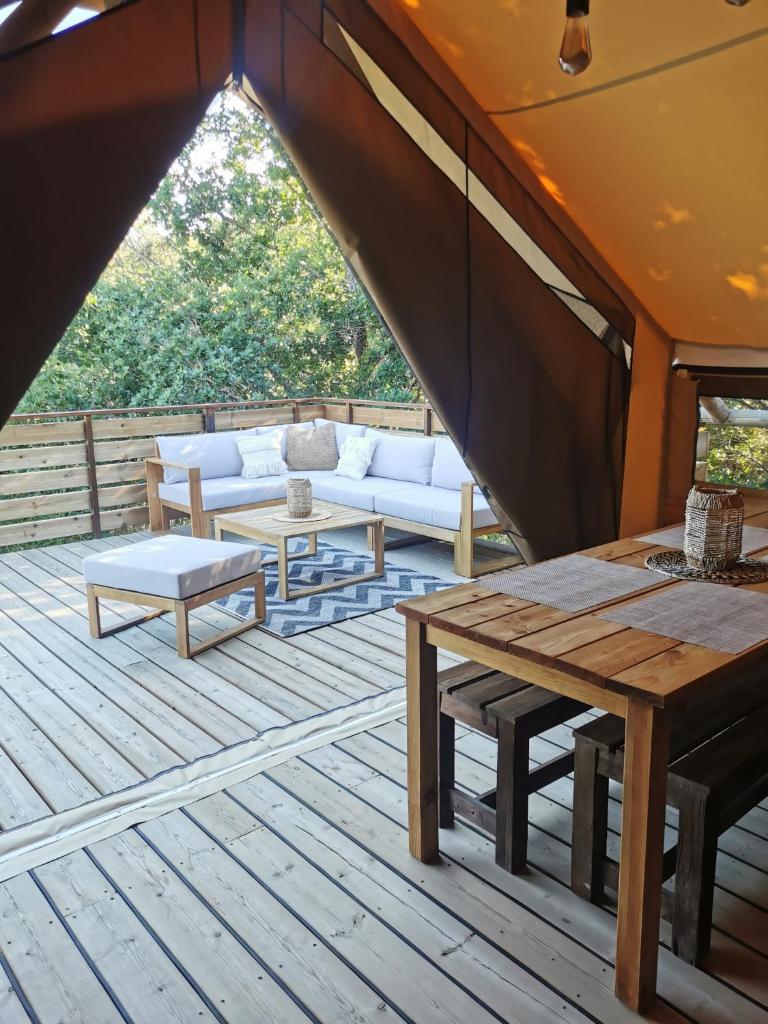 un patio avec un canapé et des tables sur une terrasse dans l'établissement Le lodge cocooning, à Ansignan