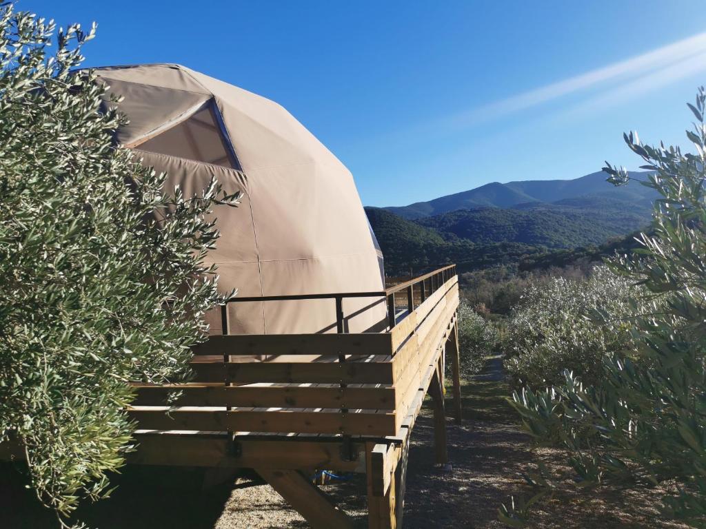une yourte avec une terrasse en bois et des montagnes en arrière-plan dans l'établissement Le dôme géodésique, à Ansignan