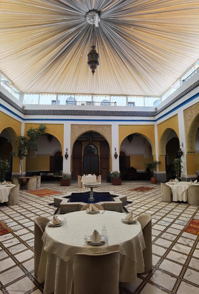 une grande chambre avec des tables et des chaises et un plafond dans l'établissement Palais didi, à Meknès