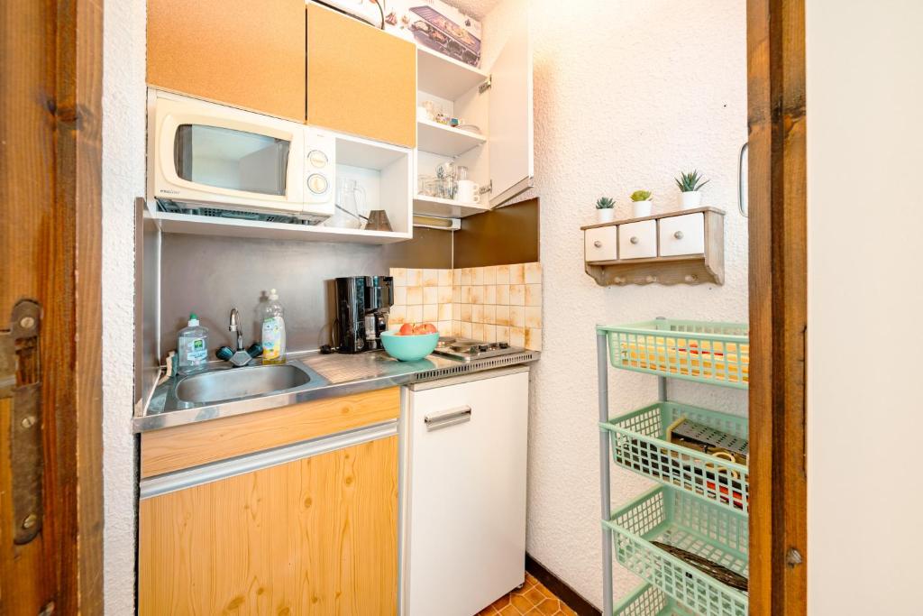 une petite cuisine avec un évier et un micro-ondes dans l'établissement Appartement au pied des pistes, à Samoëns