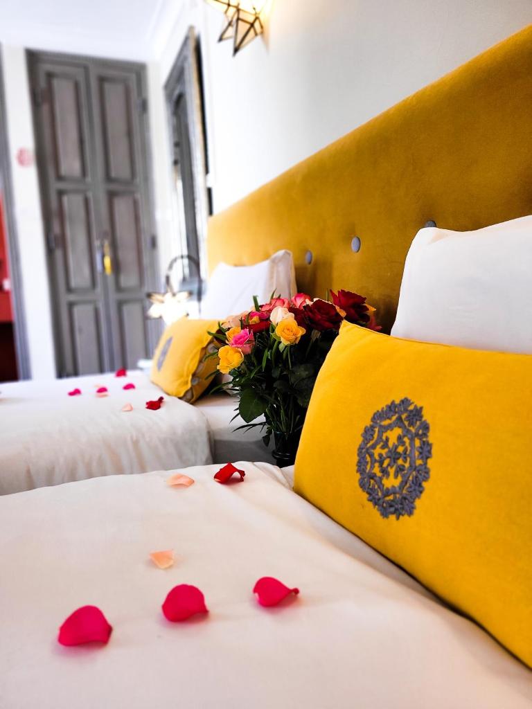 - une chambre avec 2 lits avec des pétales de rose rouge dans l'établissement Dar Andamaure, à Marrakech