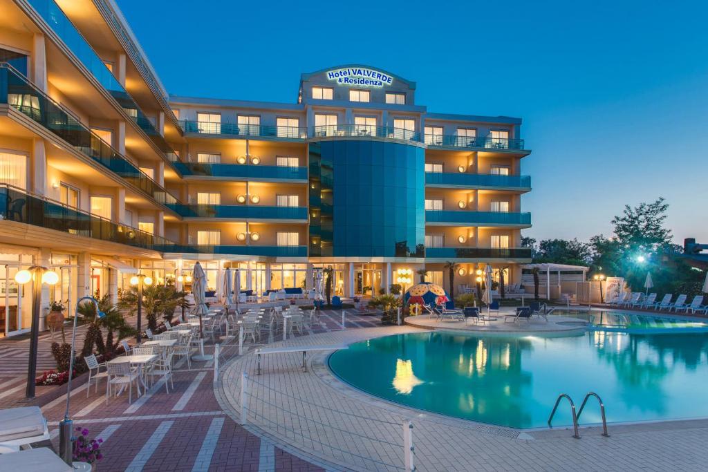 un hôtel avec une piscine devant un bâtiment dans l'établissement Hotel Valverde & Residenza, à Cesenatico