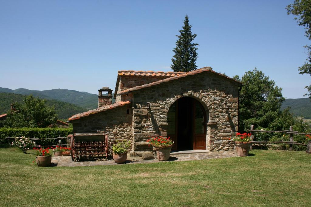 un petit bâtiment en pierre avec des fleurs dans une cour dans l'établissement Torre Di Vignale, à Palazzo del Pero