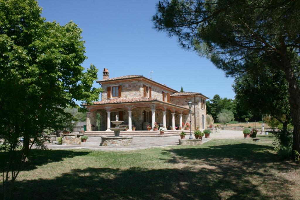 un grand bâtiment en pierre au milieu d'un parc dans l'établissement Villa Fosca, à Lucignano