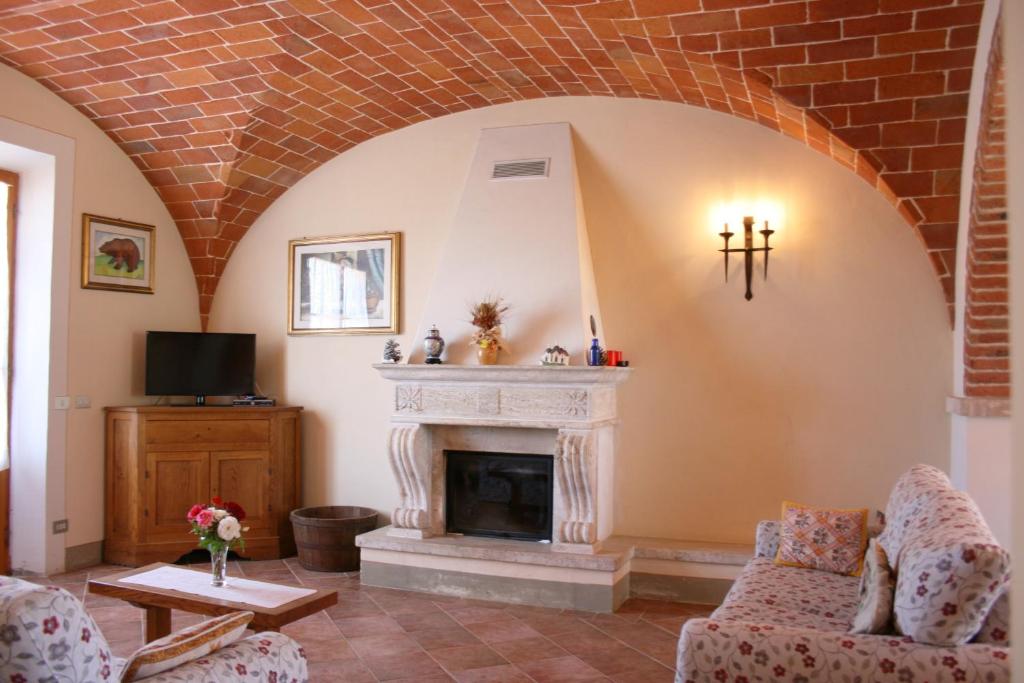 Elle comprend un salon doté d'un plafond en briques et d'une cheminée. dans l'établissement Villa Fosca, à Lucignano