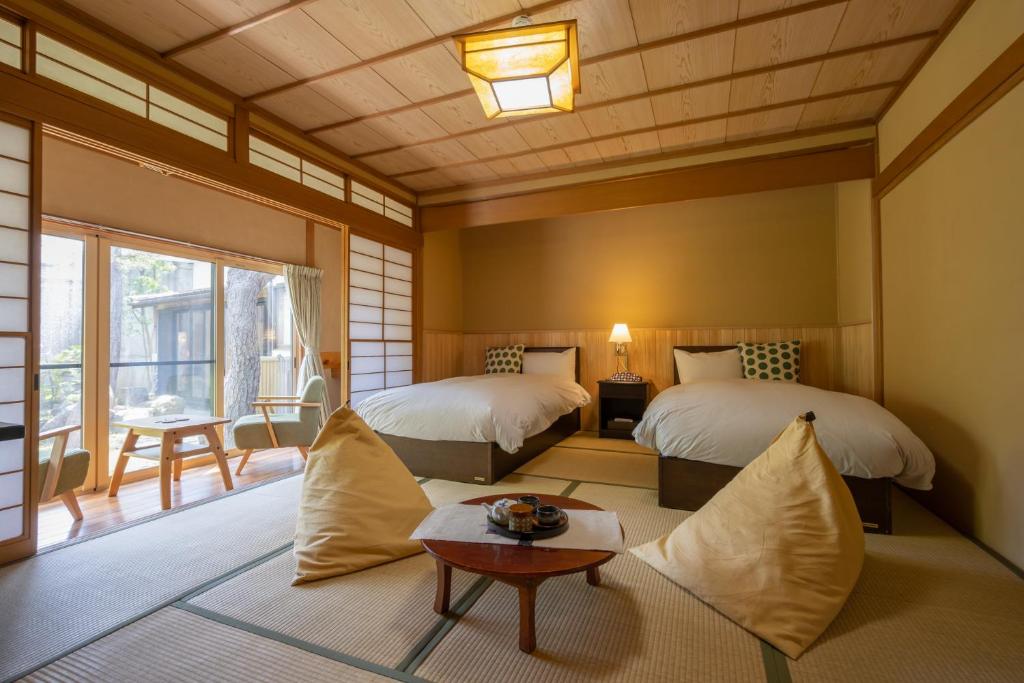 une chambre avec deux lits et une table dans une pièce dans l'établissement Kamei no Yu, à Yamanouchi