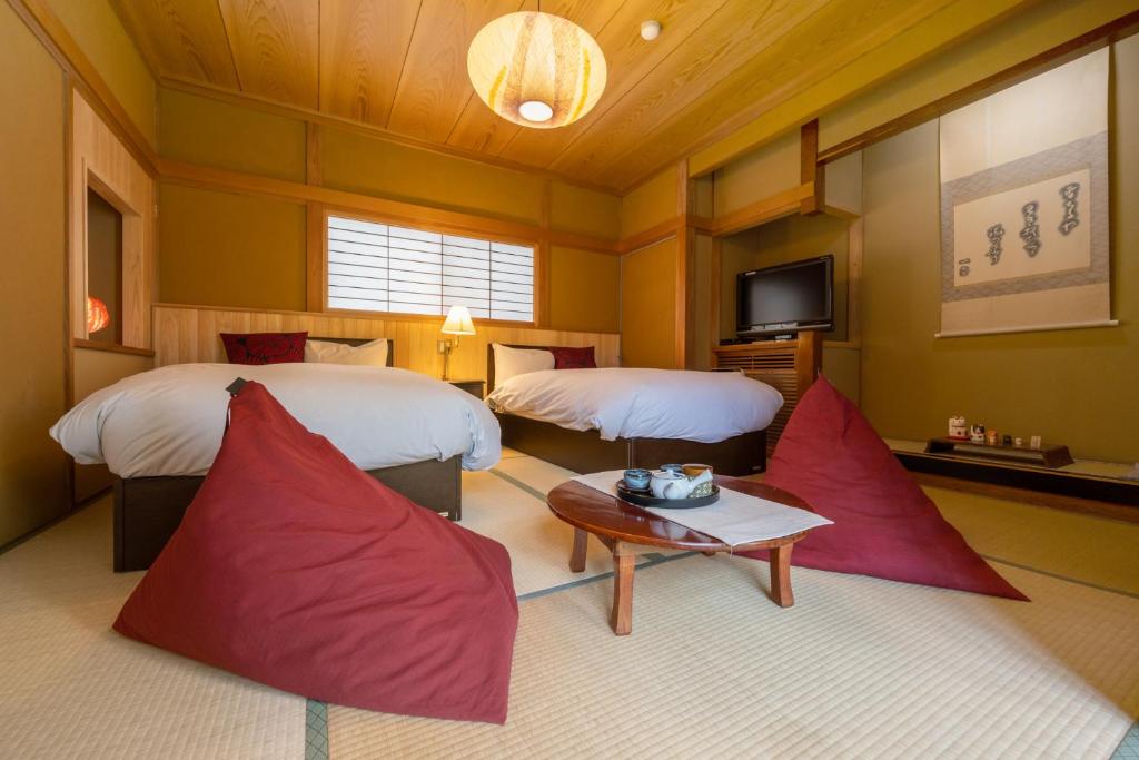 une chambre d'hôtel avec deux lits et une table dans l'établissement Kamei no Yu, à Yamanouchi