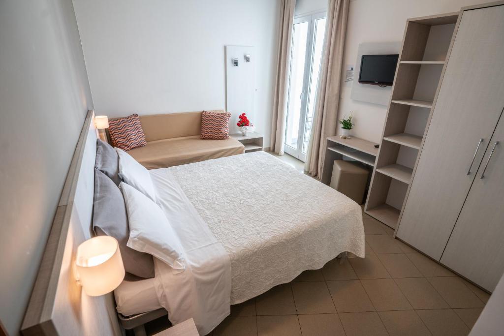 une petite chambre avec un lit et un canapé dans l'établissement Hotel Caesar, à Rimini