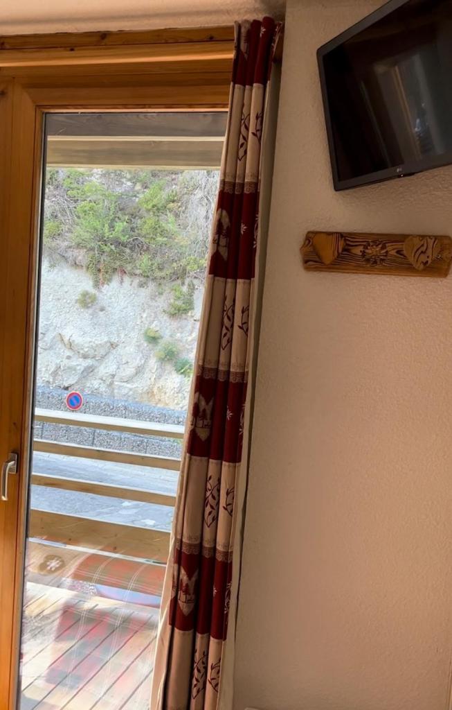 un rideau devant une fenêtre avec une télévision dans l'établissement Le chalet d'Isis - La Norma, à Villarodin-Bourget
