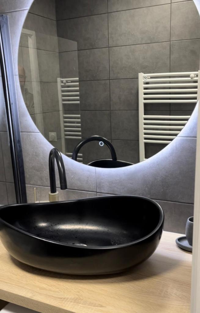 un lavabo noir devant un miroir dans l'établissement Le chalet d'Isis - La Norma, à Villarodin-Bourget