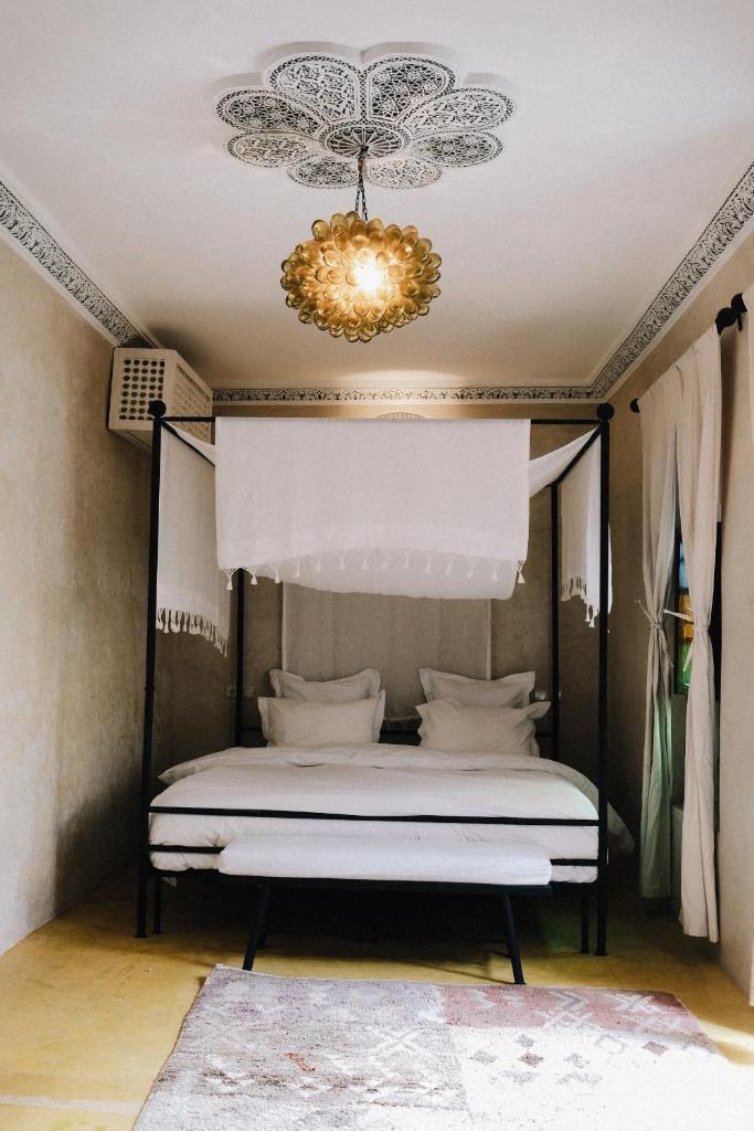 - une chambre avec un lit à baldaquin et un lustre dans l'établissement Riad Maison 24, à Marrakech