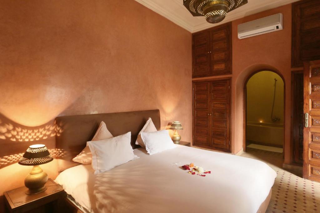 - une chambre avec un grand lit blanc orné de fleurs dans l'établissement Riad L'Emir, à Marrakech