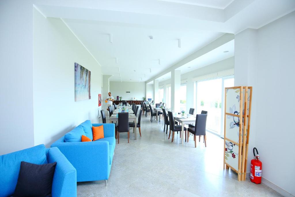 une salle à manger avec un canapé bleu, des tables et des chaises dans l'établissement Sand Hotel, à Botricello 20 autres photos