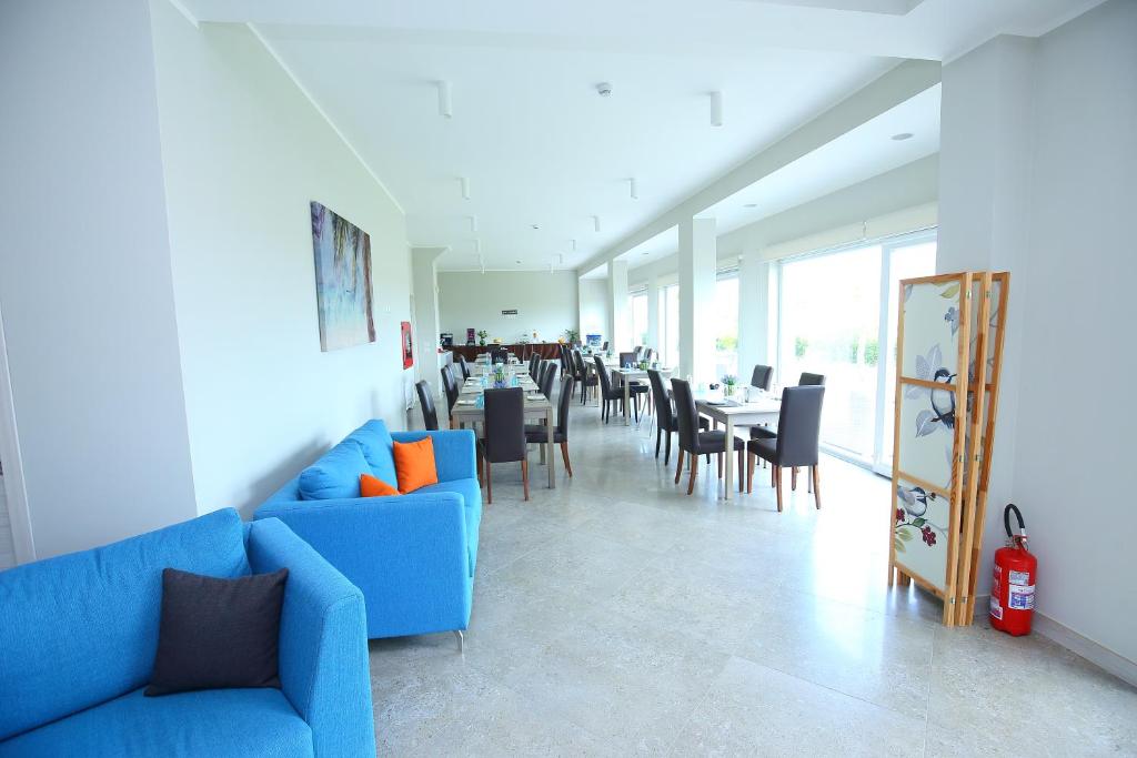 une salle à manger avec un canapé bleu, des tables et des chaises dans l'établissement Sand Hotel, à Botricello
