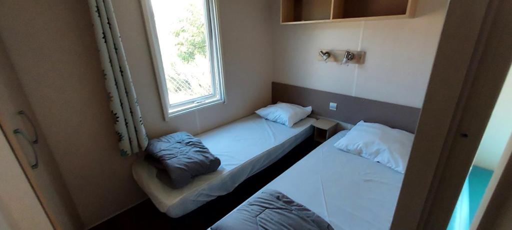 deux lits dans une petite pièce avec une fenêtre dans l'établissement Camping Les Sirènes, à Castellane