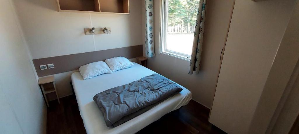 une petite pièce avec un lit et une fenêtre dans l'établissement Camping Les Sirènes, à Castellane