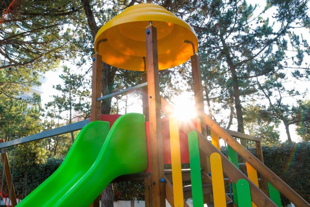 un toboggan sur une aire de jeux avec le soleil en arrière-plan dans l'établissement Hotel Principe, à Bibione