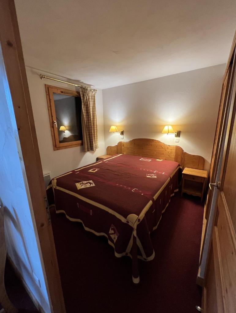 une petite chambre avec un lit avec une couverture rouge dans l'établissement Plagne Villages, Charmante Résidence de Tourisme 4 Etoiles, à Plagne Villages