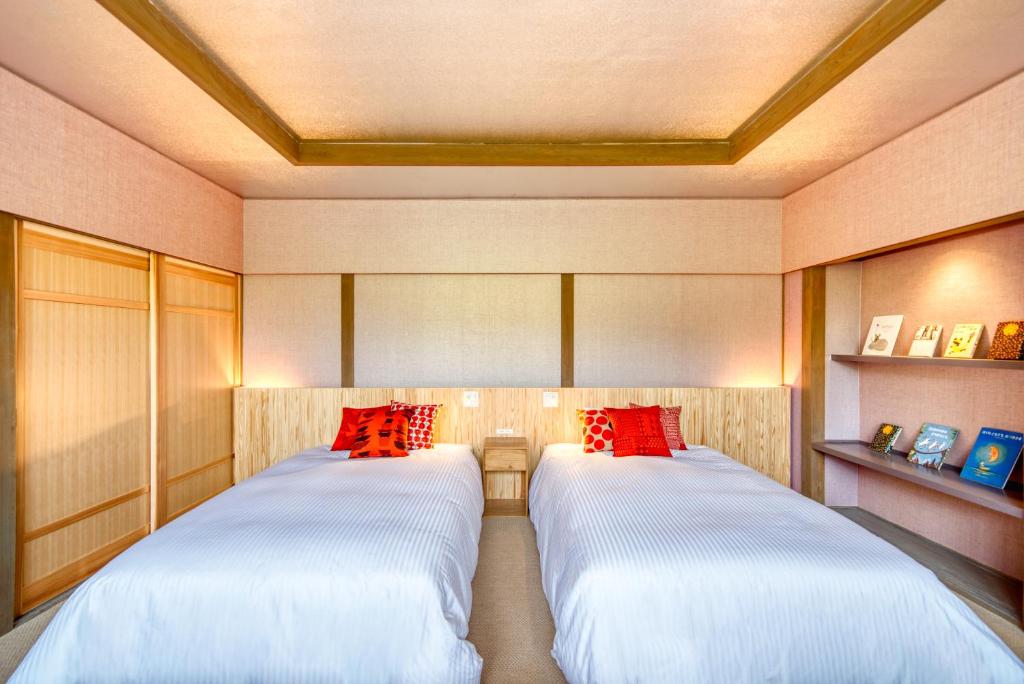 deux lits dans une chambre avec des oreillers rouges dans l'établissement Enokiya Ryokan, à Yufu 23 autres photos