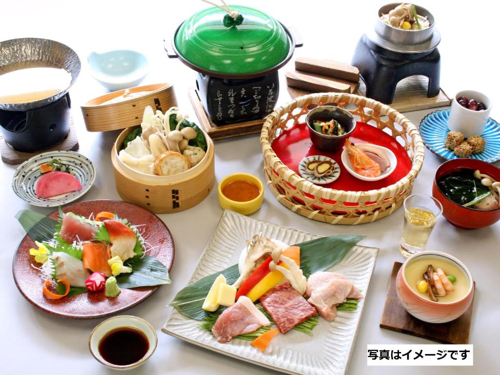 une table avec des assiettes et des bols de nourriture dans l'établissement Hotel Kameya, à Osaki