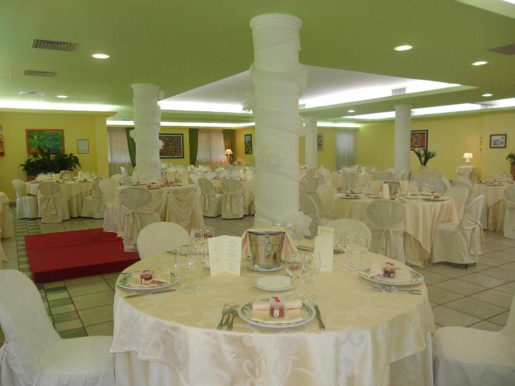 une salle de banquet avec des tables blanches et des chaises blanches dans l'établissement Hotel Parco degli Ulivi, à Scerne