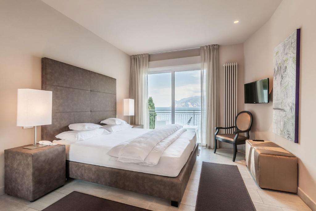 une chambre avec un grand lit et une grande fenêtre dans l'établissement Villa Tempesta, à Nago-Torbole