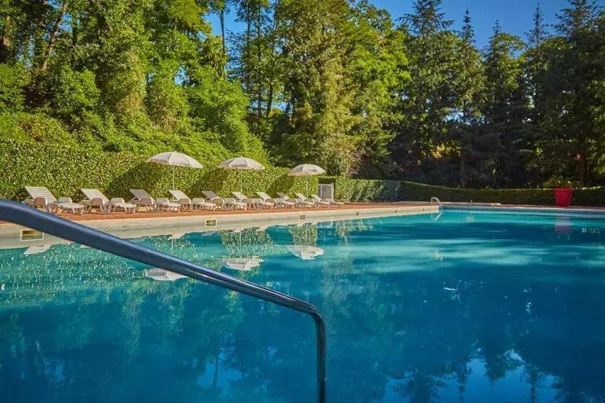 une grande piscine avec chaises et parasols dans l'établissement Mobil-House 2 chambres Saint-Chéron, à Saint-Chéron
