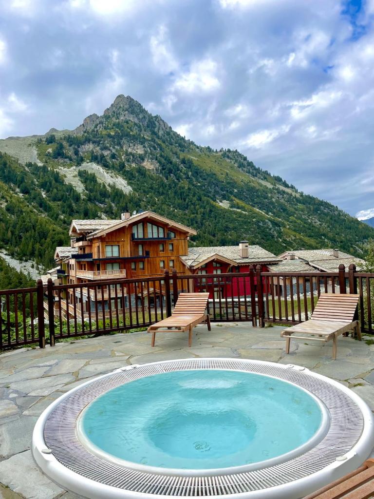 une piscine avec deux chaises et une maison dans l'établissement ARC 1950 - Appartement 5 personnes - ski aux pieds - Sauna, Hammam, Jacuzzi, à Arc 1950