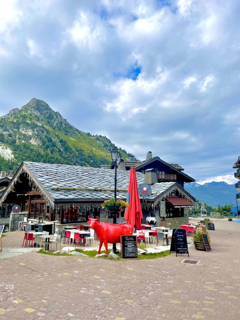 une statue d'une vache rouge devant un bâtiment dans l'établissement ARC 1950 - Appartement cosy et chaleureux - Sauna, Hammam, Jacuzzi, Piscine, à Arc 1950