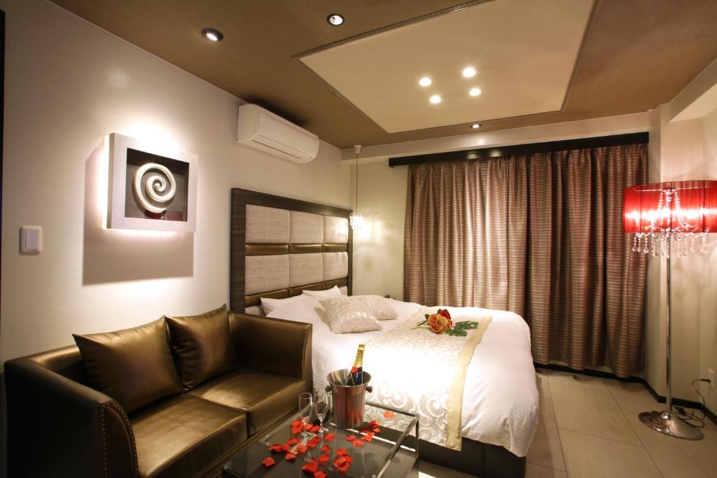 une chambre d'hôtel avec un lit et un canapé dans l'établissement ホテルコスタリゾート飯能, à Hannō