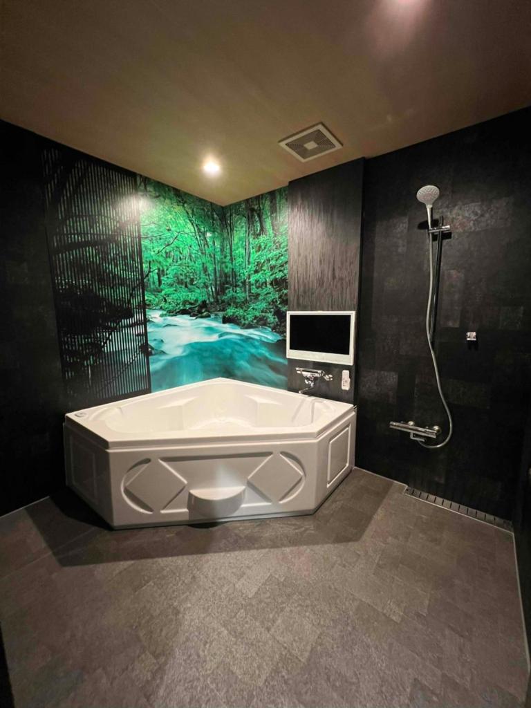 une salle de bain avec baignoire et douche et une télévision dans l'établissement Hotel Park Hill, à Sasebo