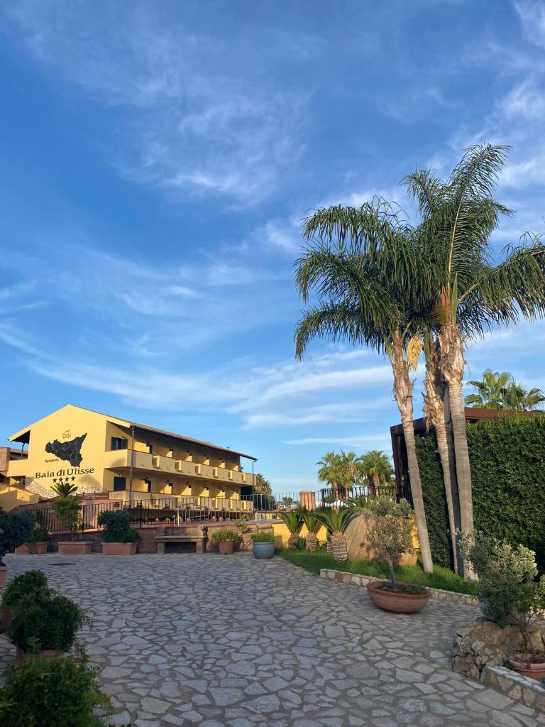 un complexe avec des palmiers devant un bâtiment dans l'établissement Baia Di Ulisse Wellness & Spa, à San Leone