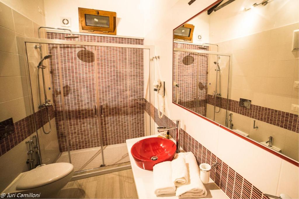 La salle de bains est pourvue d'un lavabo rouge et d'une douche. dans l'établissement Macchie San Vincenzo - Villa Privata con Piscina e Giardino ad uso esclusivo o camere, à Chiusi