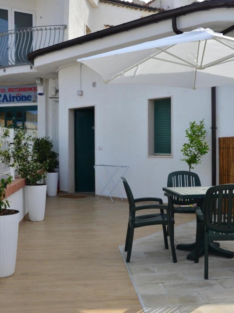 un patio avec deux chaises, une table et un parasol dans l'établissement Residence Airone, à Termoli