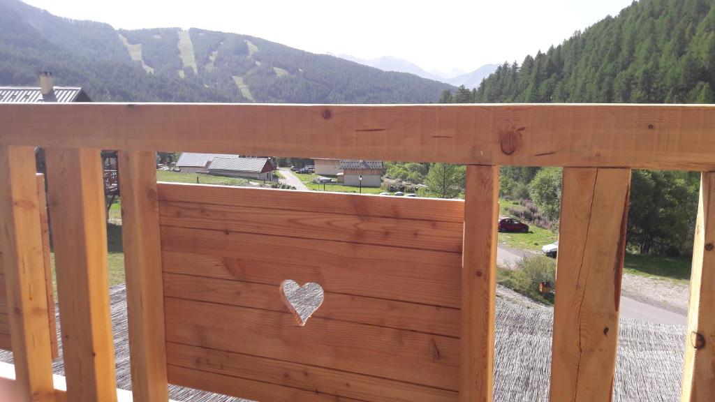 une balustrade en bois avec un cœur sur un balcon dans l'établissement Les Balcons de L'Izoard, à Arvieux
