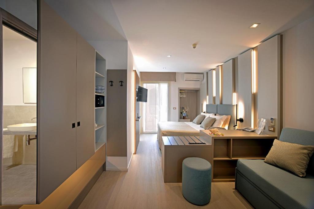 - un salon avec un canapé et un lit dans une chambre dans l'établissement Hotel Colorado, à Lignano Sabbiadoro