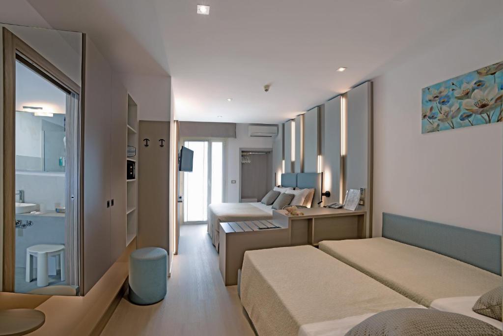 une chambre d'hôtel avec deux lits et une salle de bain dans l'établissement Hotel Colorado, à Lignano Sabbiadoro