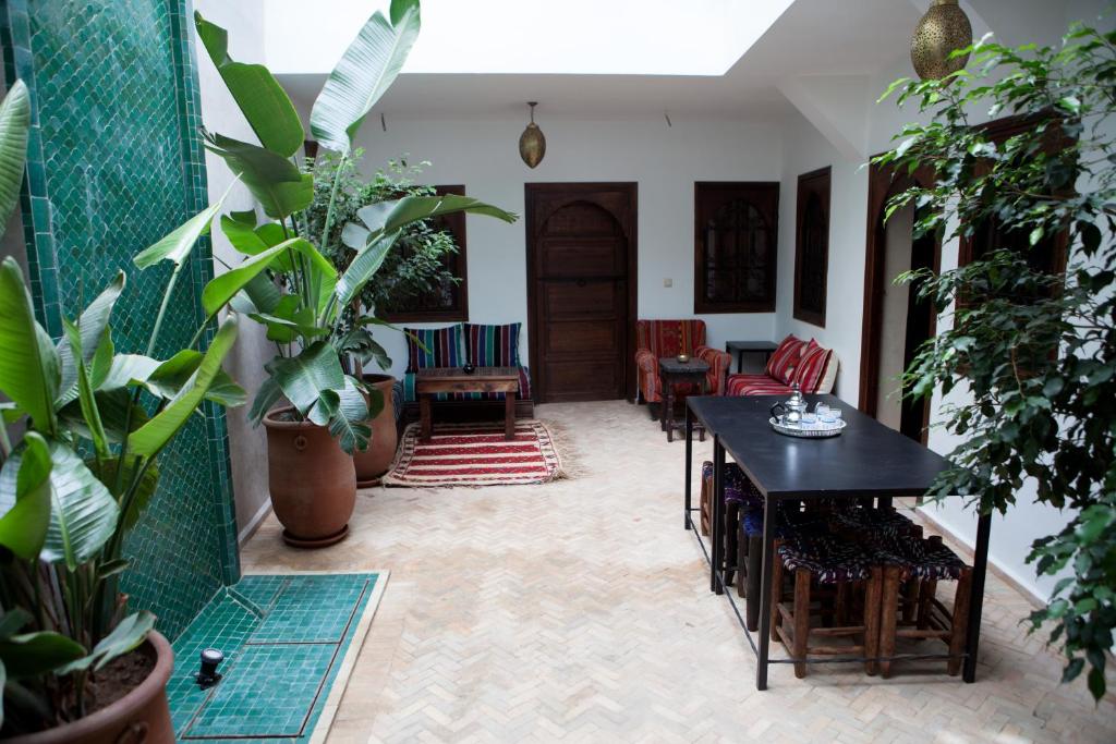une pièce avec des plantes, une table et des chaises dans l'établissement Riad Achwaq, à Marrakech