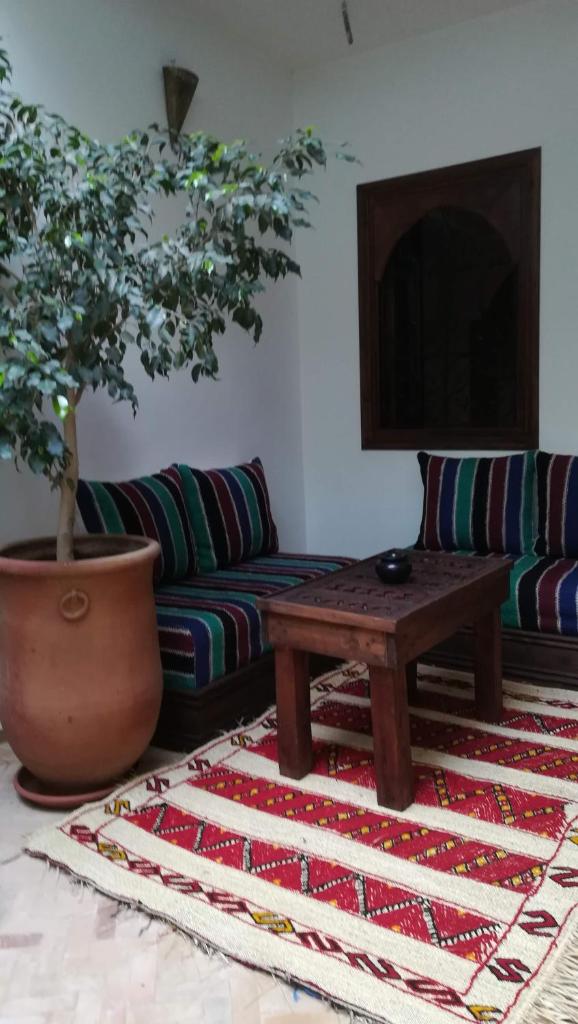 - un salon avec un canapé, une table et un arbre dans l'établissement Riad Achwaq, à Marrakech