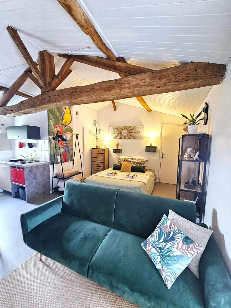 un salon avec un canapé vert et un lit dans l'établissement Gite "RIO", parking securise, à La Roche-sur-Yon