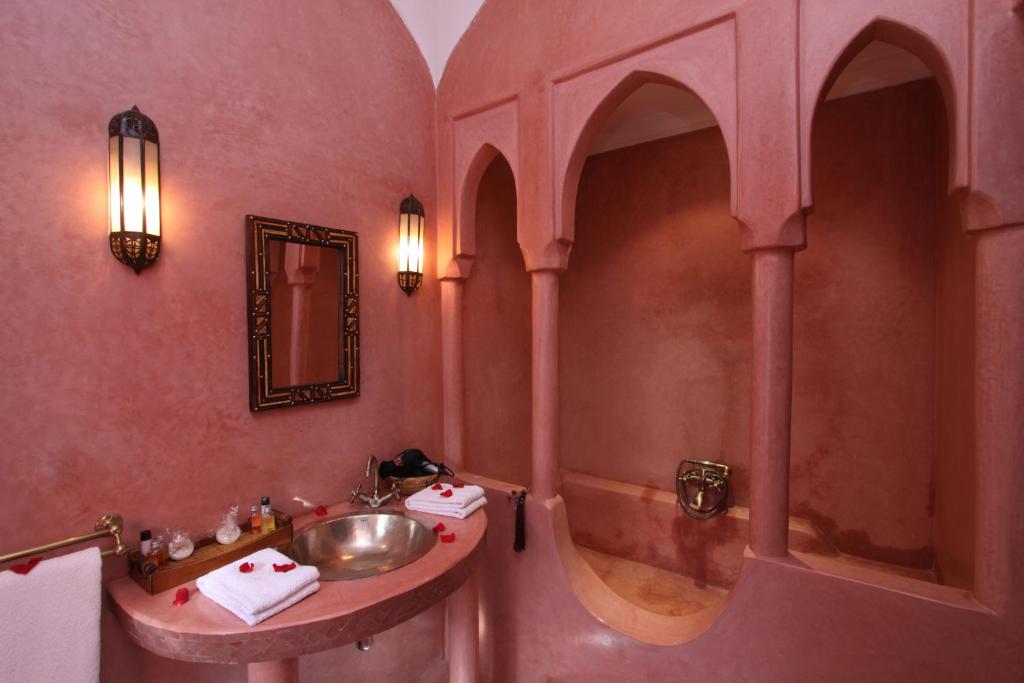 La salle de bains rose est pourvue d'un lavabo et d'une douche. dans l'établissement Riad Cannelle, à Marrakech