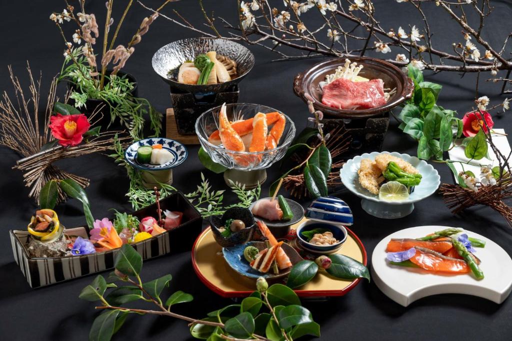 une table avec de nombreuses assiettes de nourriture dessus dans l'établissement Sado Resort Hotel Azuma, à Sado