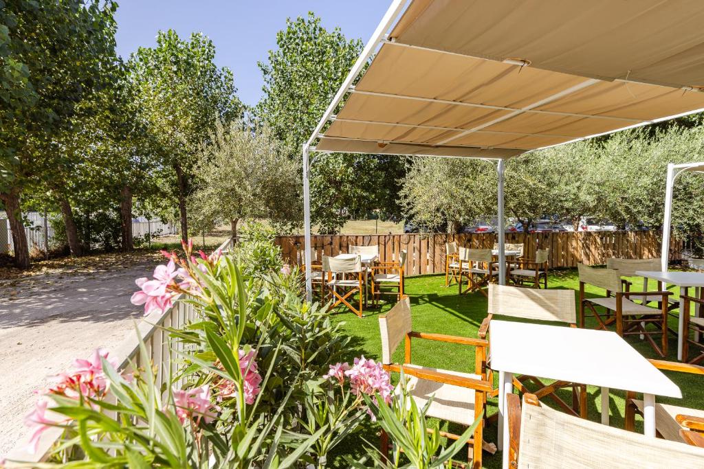une terrasse avec des tables, des chaises et des fleurs dans l'établissement Hotel Sorriso, à Misano Adriatico
